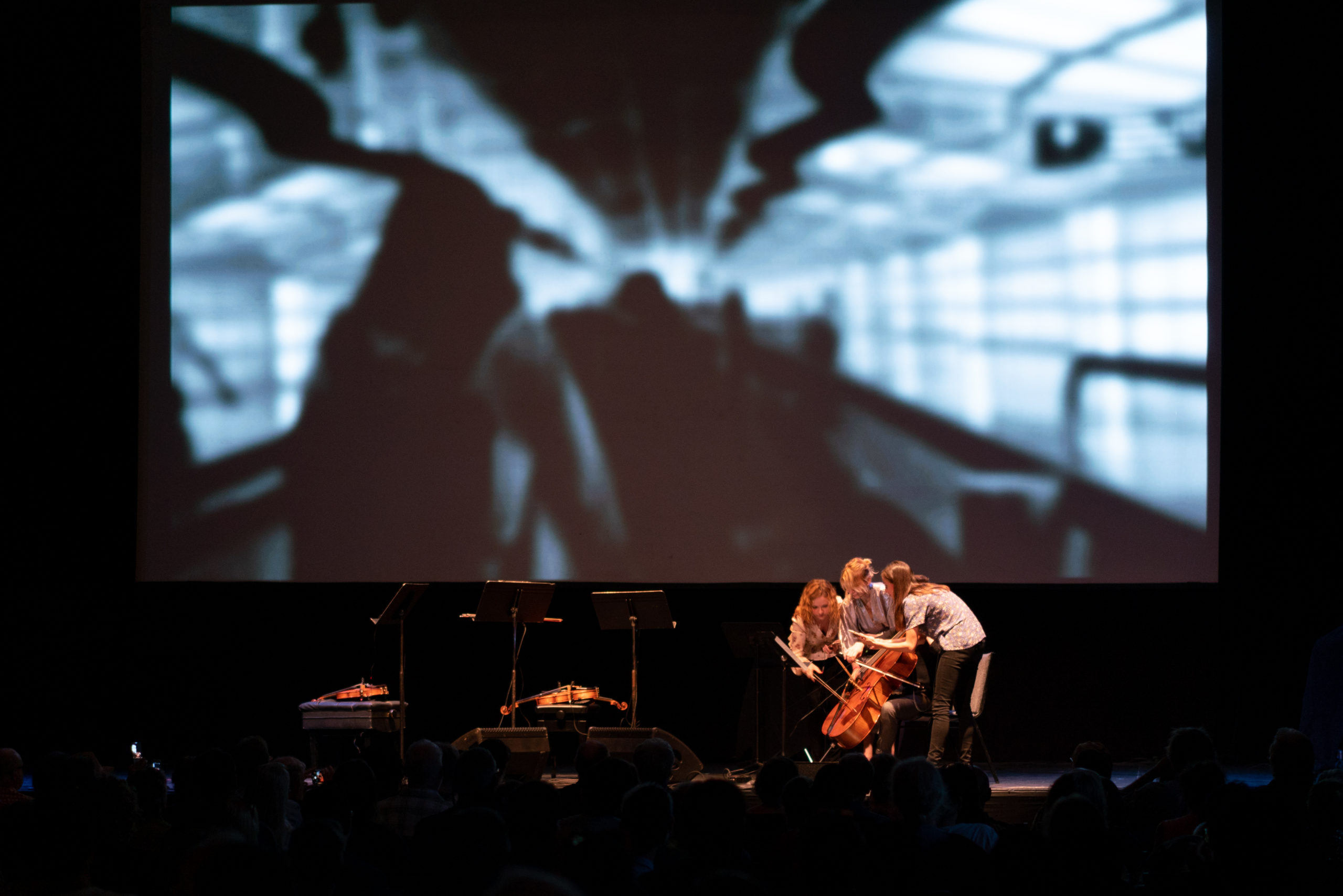 Holly Workman, violin, performing Pamela Z Attention during a concert. Four musicians are all playing one cello