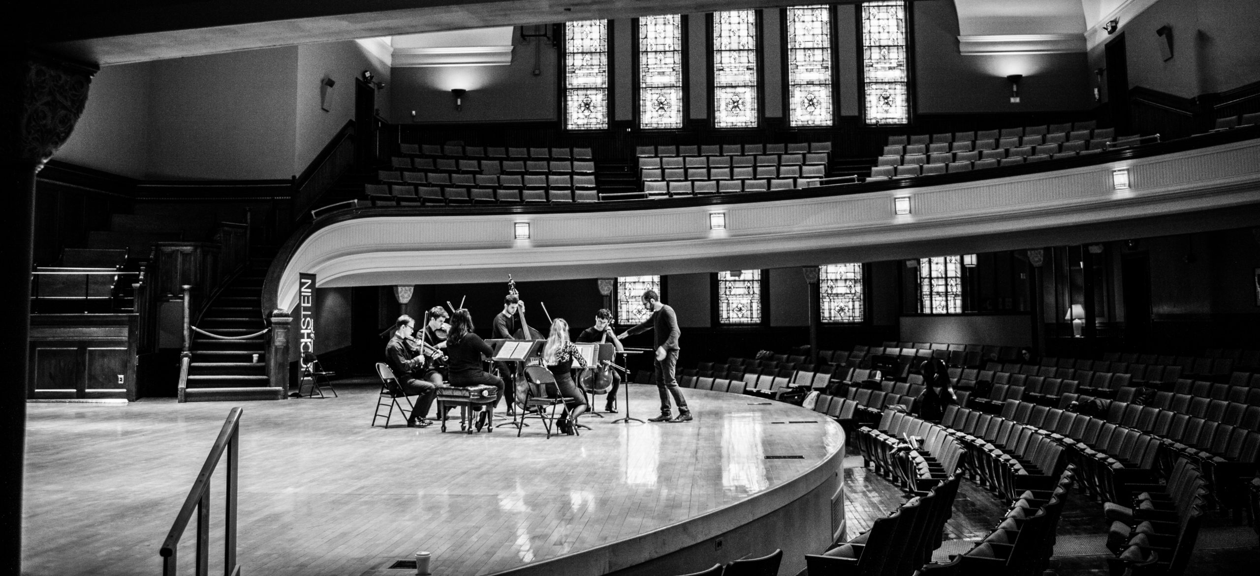 Holly Workman, violinist, performing in a conducted ensemble in a large hall.