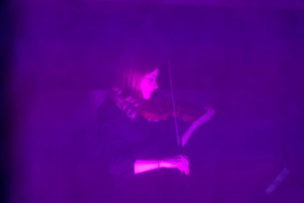 Violinist Holly Workman performing behind a purple screen at the CRESC. Festival